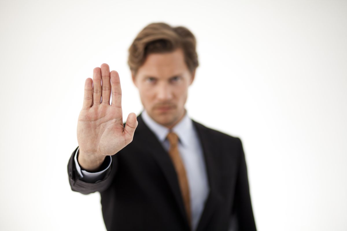 A man in a suit gesturing for someone to stop right there