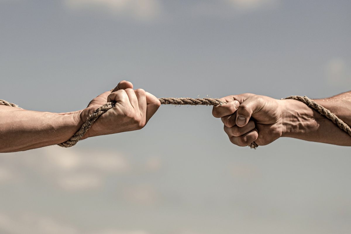 Two hands holding a rope contesting a tug of war