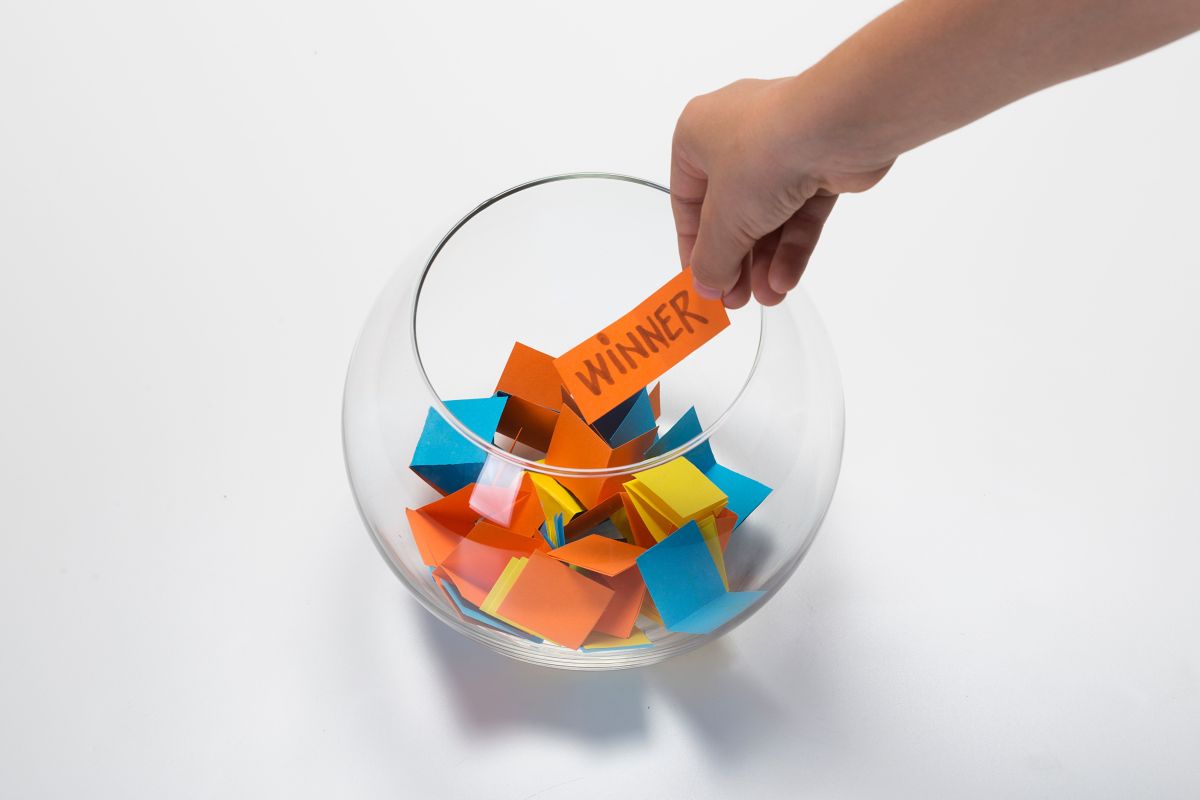 A person pulling a raffle ticket from a bowl