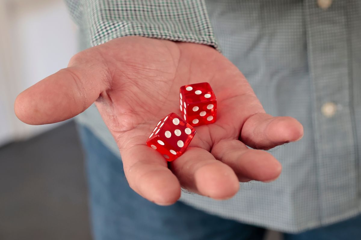 A man holding a pair of dice in his hand as if considering whether to roll them
