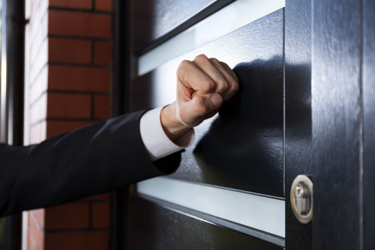 A person banging at a door, implying enforcement action at a business