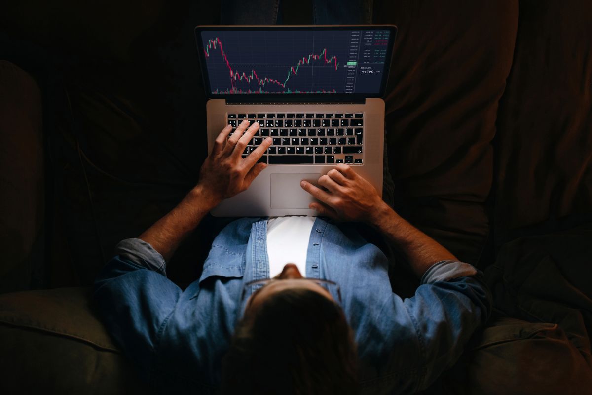 An overhead shot of a man trading stocks on a laptop