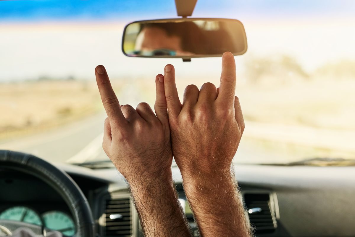 Tow people in a car making the Hard Rock "rock on" hand gesture