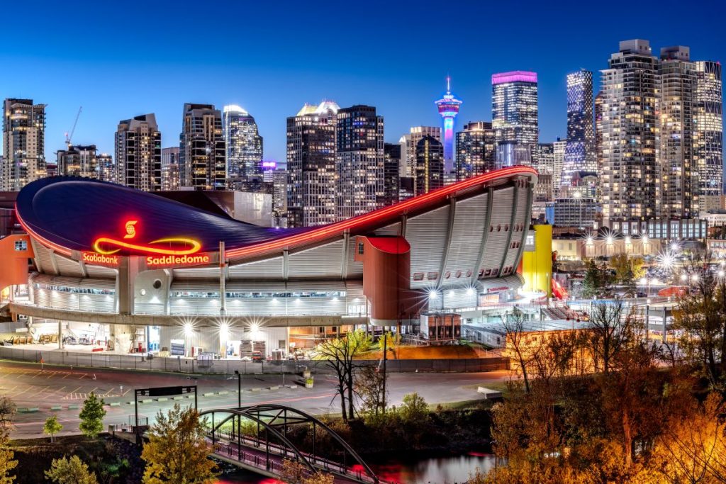 Calgary's downtown at night with the Scotiabank Saddledome in the foreground. The dome is home to the Calgary Flames NHL team