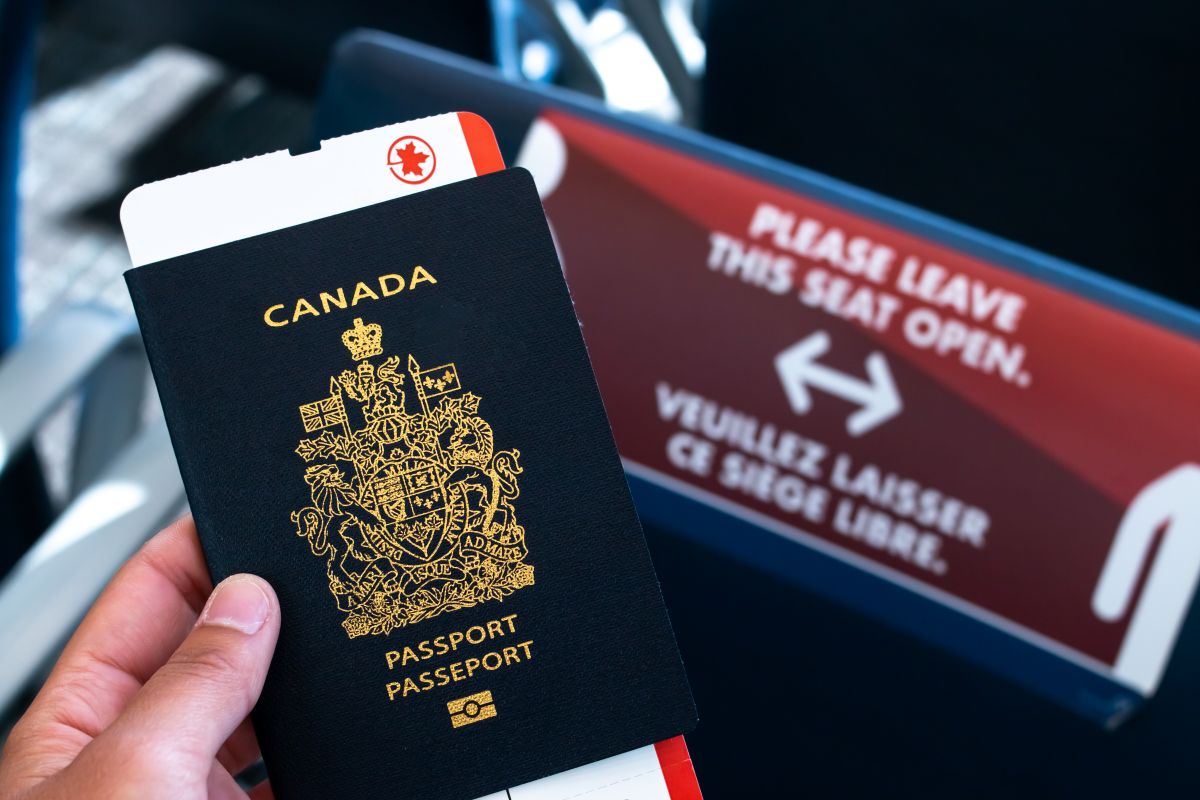 A person holding a Canadian passport with a plane ticket inside