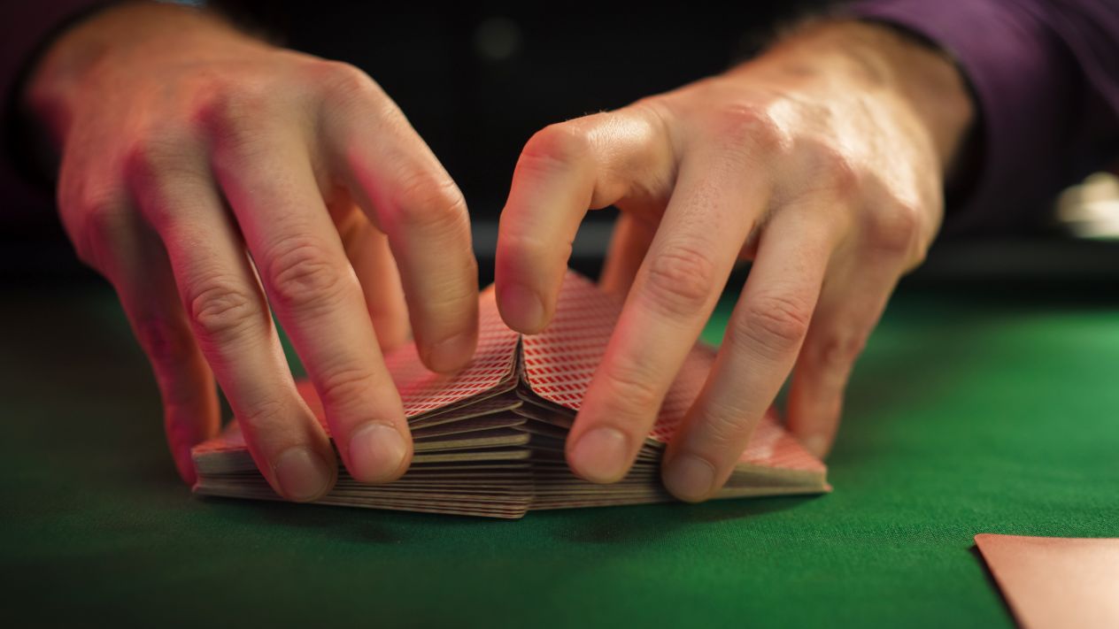 A table games dealer at a casino shuffles a deck of cards