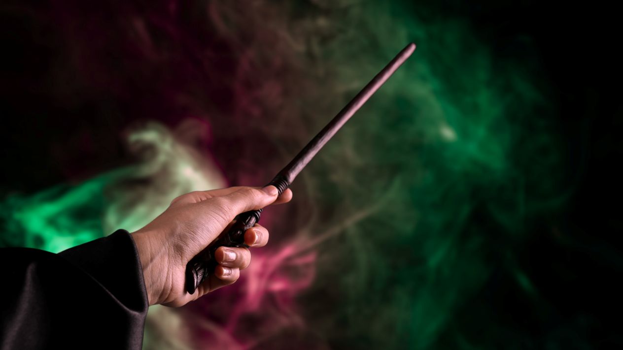A person's hand holding a wand like a wizard