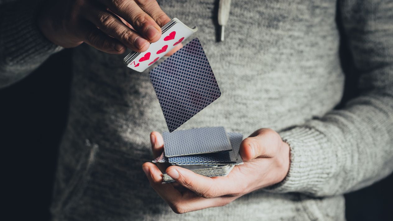 A close up of a man's hands shuffling a deck of cards