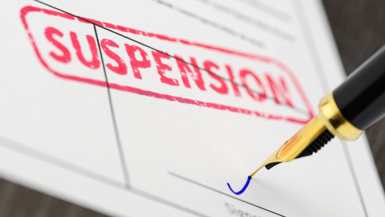 A fountain pen signing a notice of suspension