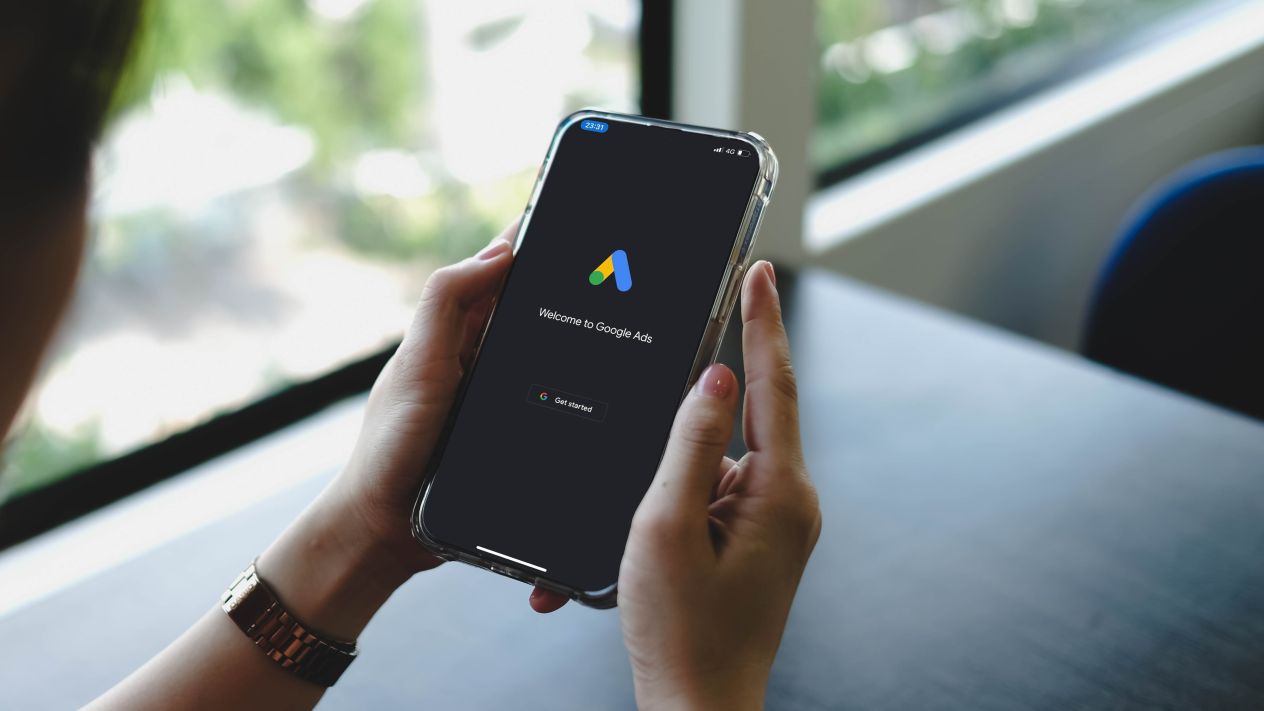 A person holding a phone as it displays Google Ads