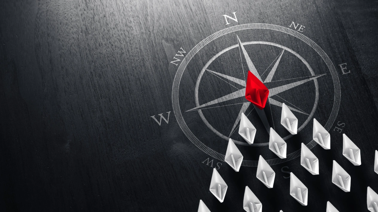 A paper boat leads the way over a compass, illustrating iGaming's direction in Canada.